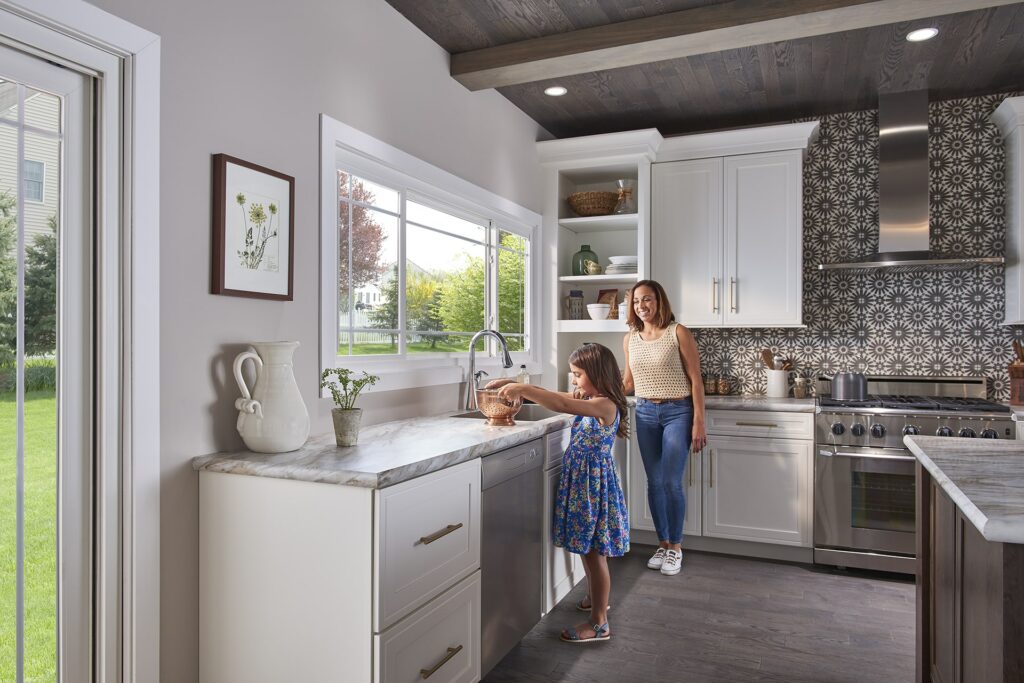 Mother and daughter cooking in kitchen in front of bay window