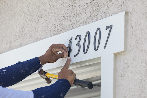 man installing house numbers
